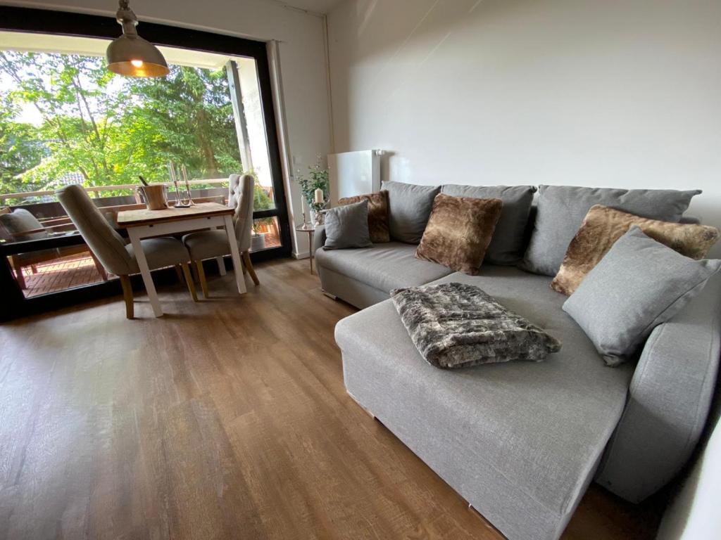 a living room with a gray couch and a table at Chalet-Apartment Waldfrieden, in ruhiger Lage mit TG in Hahnenklee-Bockswiese