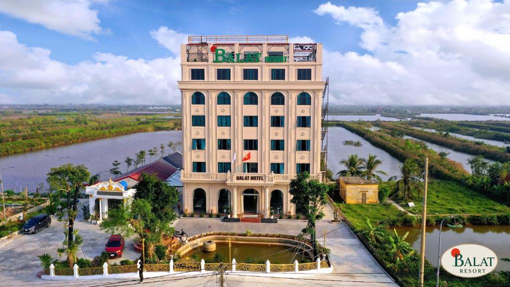 a tall white building next to a river at Balat Resort in Tập Thiện