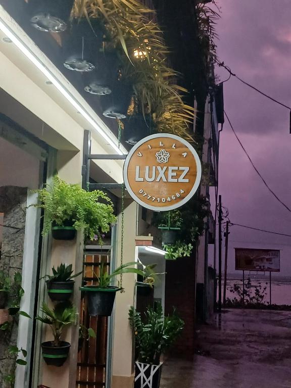 a sign on the side of a building with plants at Villa Luxez in Kalmunaikudiyiruppu