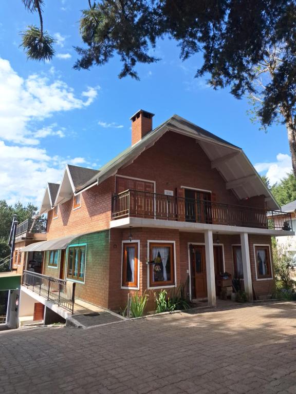 a large brick house with a balcony on it at Recanto Ursa Maior in Monte Verde