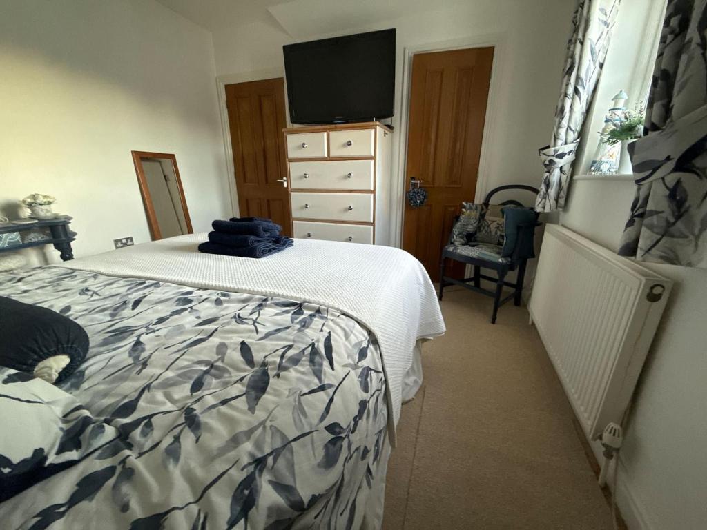 a bedroom with a bed and a dresser with a television at Our Garden View Room in Bedford