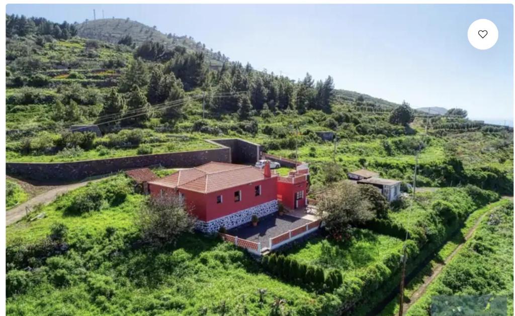 a red house on a hill in a green field at CASA VILA in Garafía