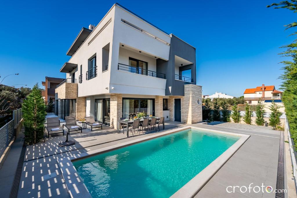 a house with a swimming pool in front of it at Villa Tamaris- 10 mins from Zadar in Zadar