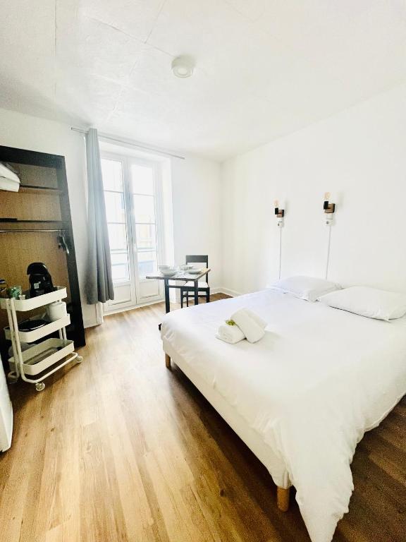 a white bedroom with a large bed and a table at Apparthotel Beauregard 12 cœur de Nantes WIFI in Nantes