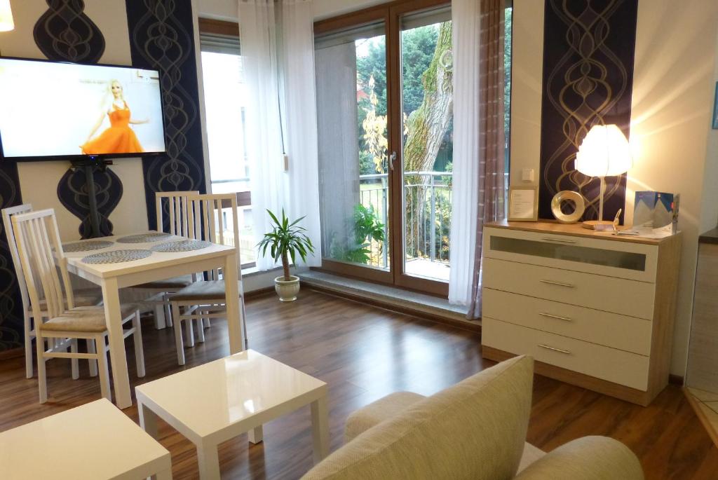Una sala de estar con un televisor y una mesa y sillas. en SAS Apartamenty Baron, en Szczecin