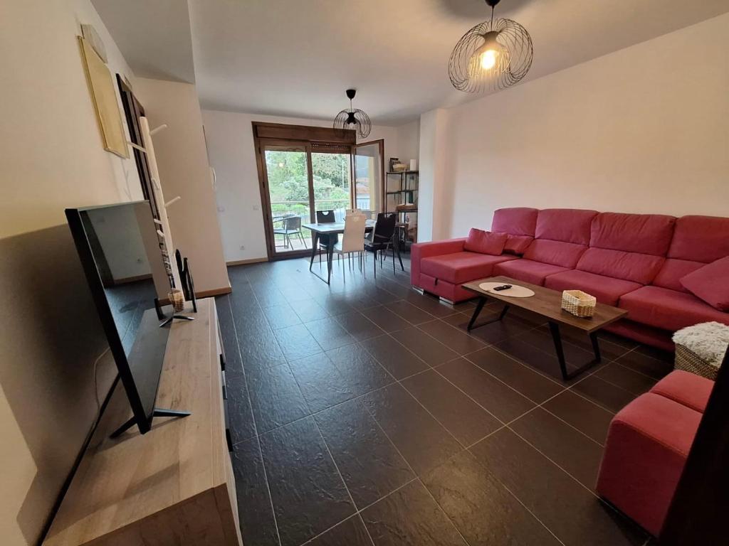 a living room with a red couch and a tv at Aldea Bricia 201 in Posada de Llanes