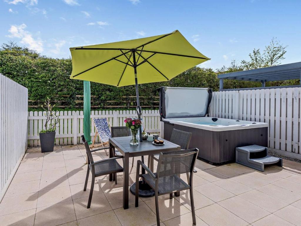 a patio with a table with a yellow umbrella and a tub at 2 Bed in Bideford oc-91748 in Northam