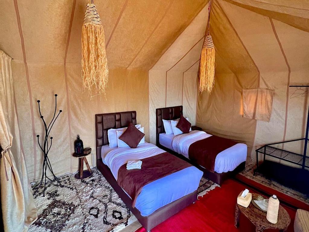 a bedroom with two beds in a tent at Big Dipper Luxury Camp in Merzouga
