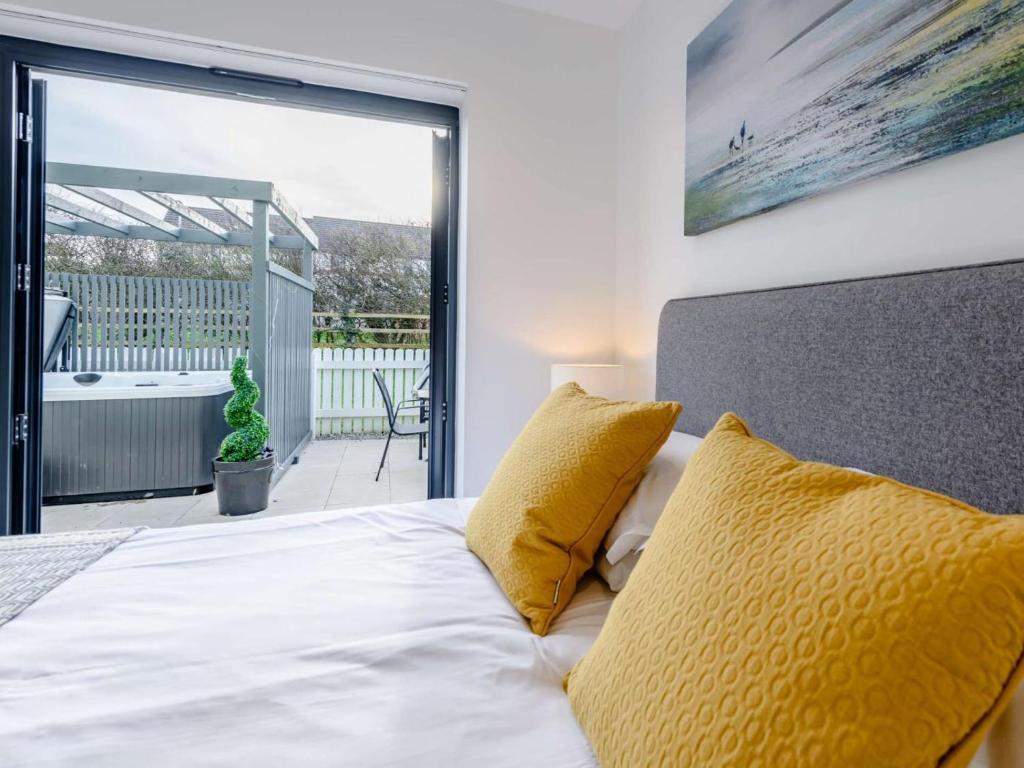 a bedroom with a bed with yellow pillows and a balcony at 2 Bed in Bideford oc-77289 in Northam