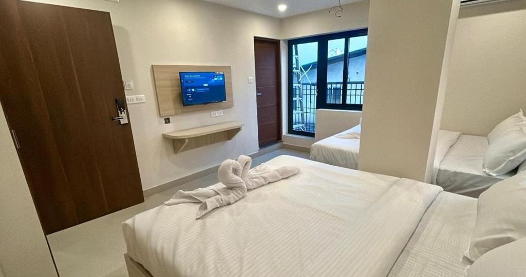 a hotel room with two beds and a television at Tresor Hotel in Cochin