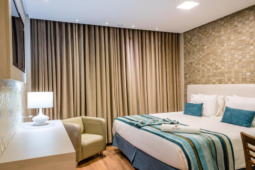 a hotel room with a large bed and a large window at Vogue Hotel Rio in São João de Meriti