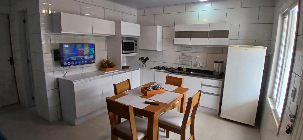 a kitchen with a table and chairs and a refrigerator at Casa reformada com Wi-Fi, garagem e lavanderia in Capão da Canoa