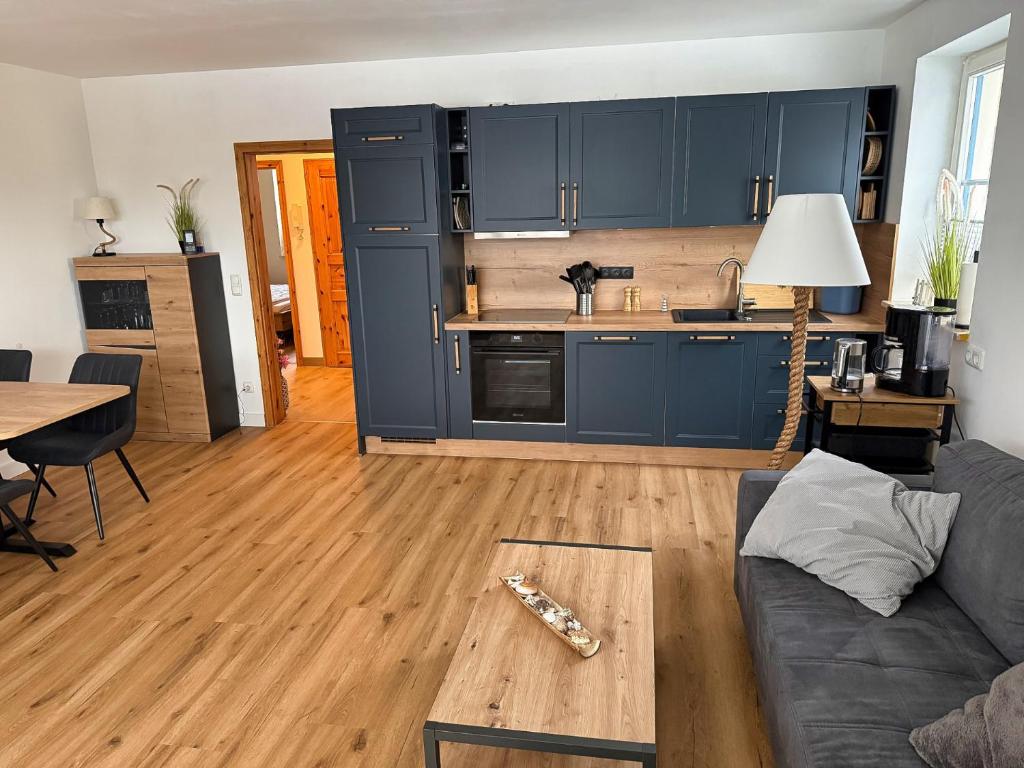 a living room with blue cabinets and a wooden floor at Ferienwohnung Meeresleuchten - Glowe in Glowe