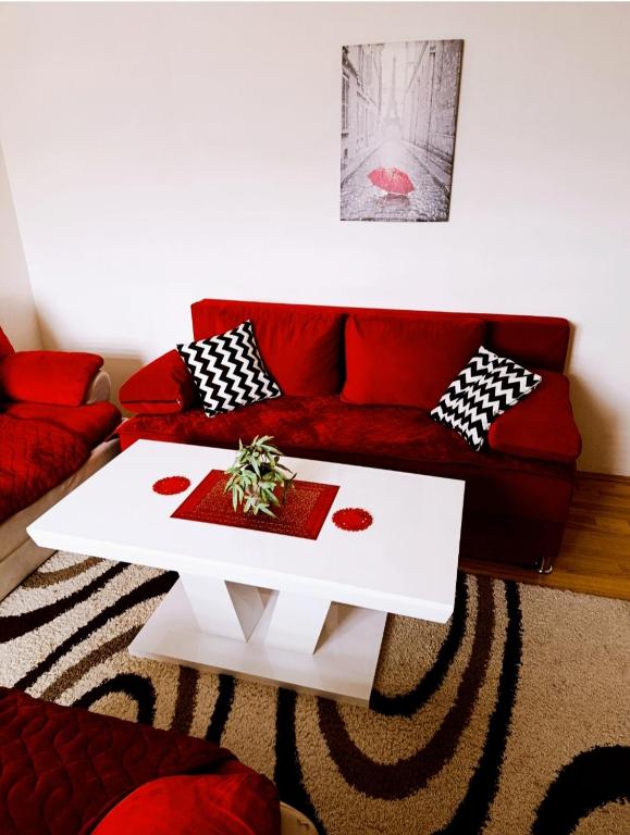a living room with a red couch and a white coffee table at Apartman 053 in Doboj