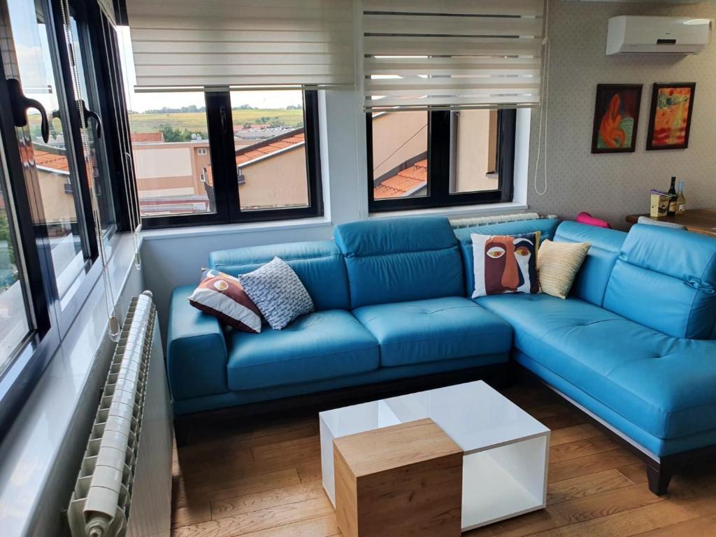 a living room with a blue couch in a train at Alo Alo Apartman 5 in Kruševac