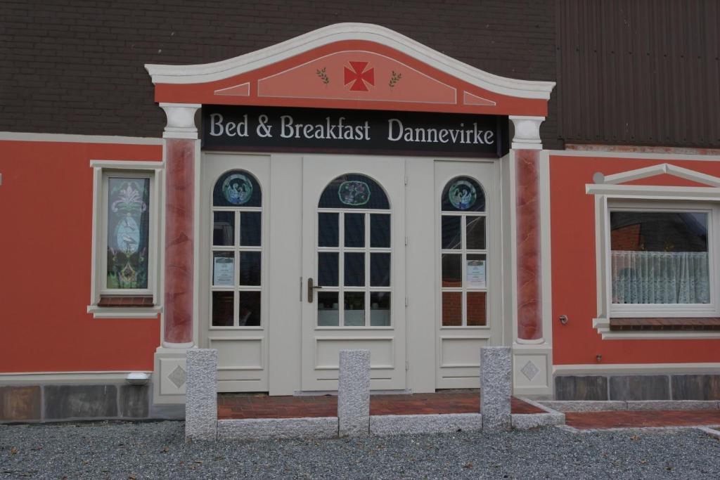 un edificio rojo y blanco con un cartel en él en Bed and Breakfast Dannevirke en Owschlag