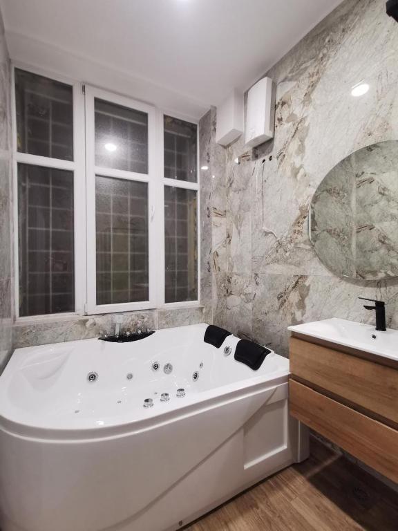 a large white bath tub in a bathroom with a sink at 369 Apartments in Belgrade