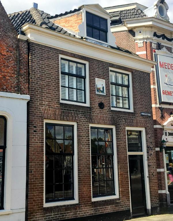 a brick building with black windows on a street at De Kleine Prins Enkhuizen in Enkhuizen