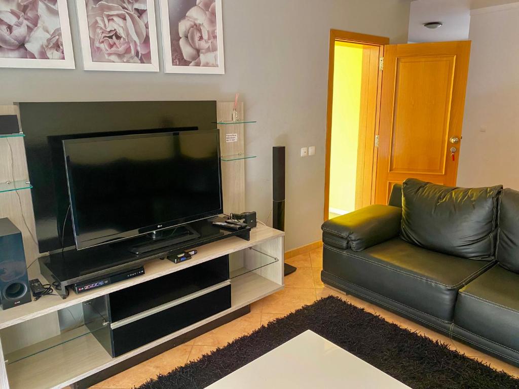 un salon avec un canapé en cuir noir et une télévision à écran plat dans l'établissement Apartamento espaçoso, à Santa Maria