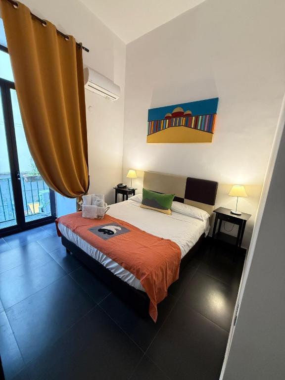 a bedroom with a bed with an orange blanket at Hotel Plebiscito Aparthotel in Naples