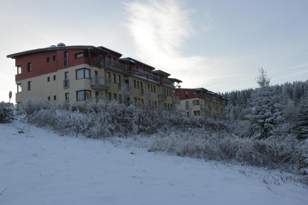 a building in a field with snow in front of it at Ski apartman Klinovec in Loučná pod Klínovcem
