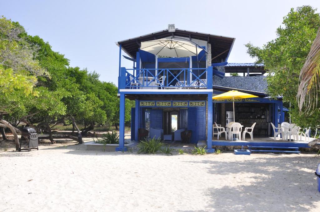 Casa Gaviota Baru Beach House في بارو: مبنى أزرق على طاولات وكراسي على الشاطئ