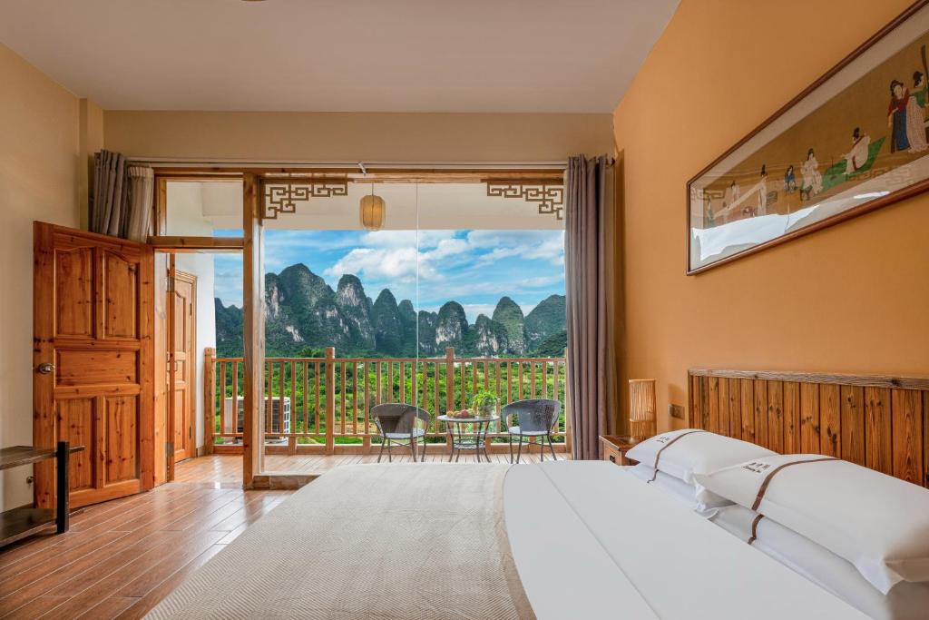 a bedroom with a bed and a balcony with mountains at Serenity Inn in Gaotian