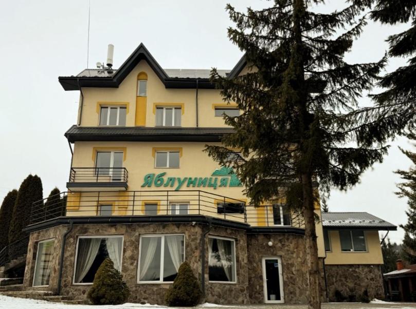 a large yellow building with a sign on it at Готель Яблуниця in Yablunytsya