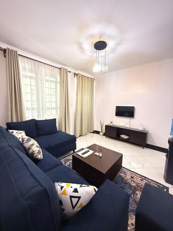 a living room with a blue couch and a tv at Beytumn Luxury Apartment - Ruiru in Nairobi