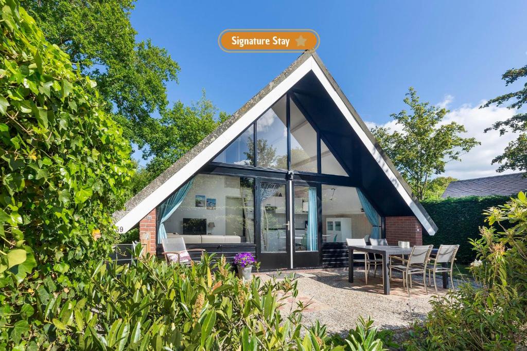 a house with a triangular roof with a table and chairs at Jonkerstee 59 - Ouddorp in Ouddorp