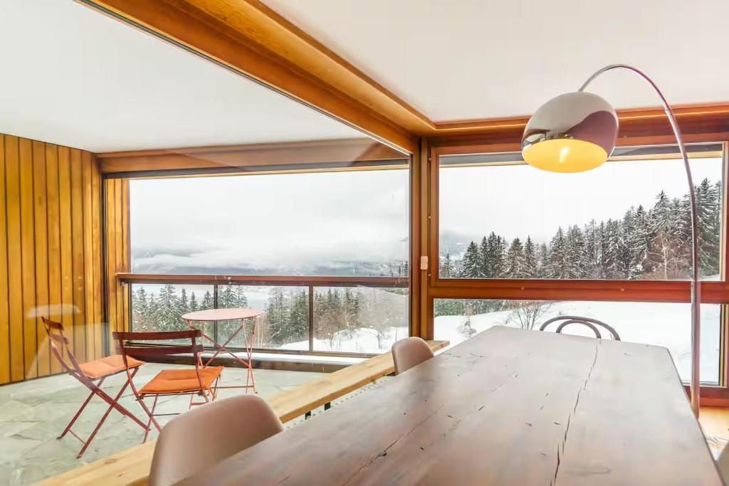 a dining room with a table and chairs and a large window at Alpine Panorama Spacious Mountain Retreat in Crans-Montana