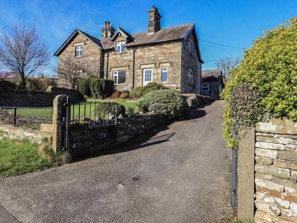 an old brick house with a gate in a driveway at 2 Lupton Hall Cottages in Carnforth