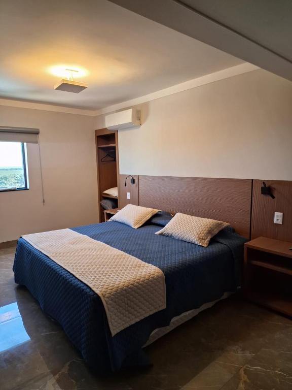 a bedroom with a bed with a blue comforter at Optimum Plaza Hotel in Monte Alto