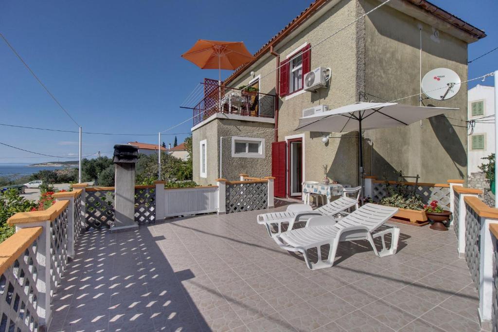a patio with chairs and an umbrella and a building at Apartments Tasha in Štivan