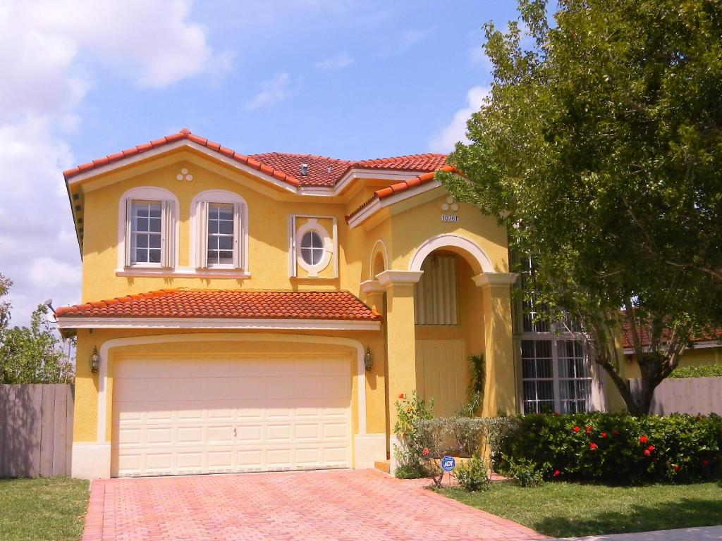 a yellow house with a garage in front of it at My Florida Lake House in Homestead