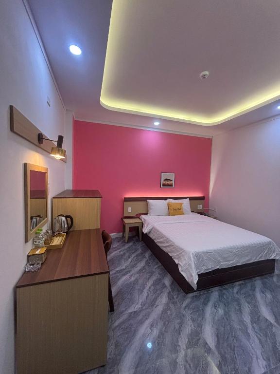 a bedroom with a bed and a pink wall at Spring II Hotel in Ấp Bình Hòa (1)