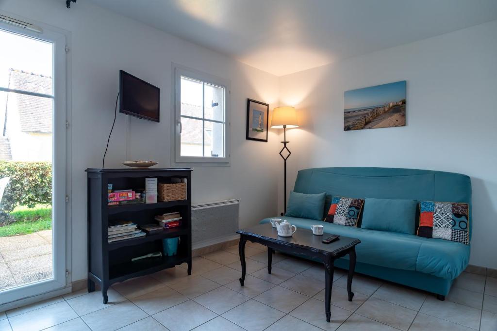 a living room with a blue couch and a table at Pentrez Cottage - 600m de la Plage in Saint-Nic