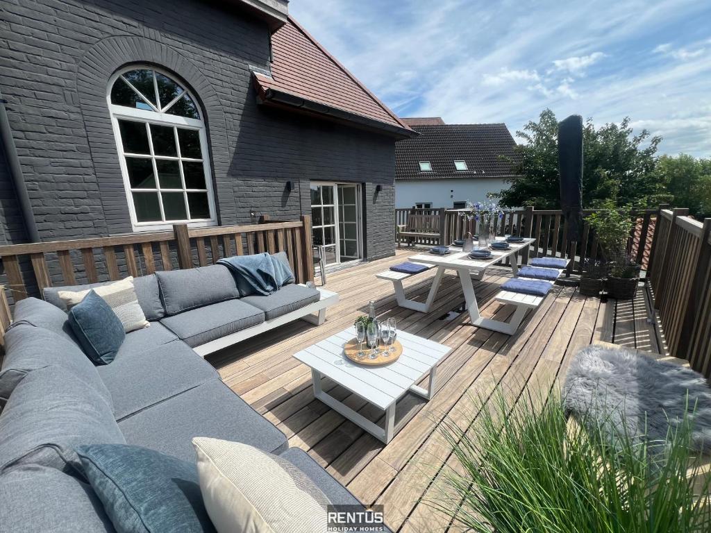 a patio with couches and tables on a wooden deck at Villa Promenade - luxuriously apartment for 8 people in Nieuwpoort