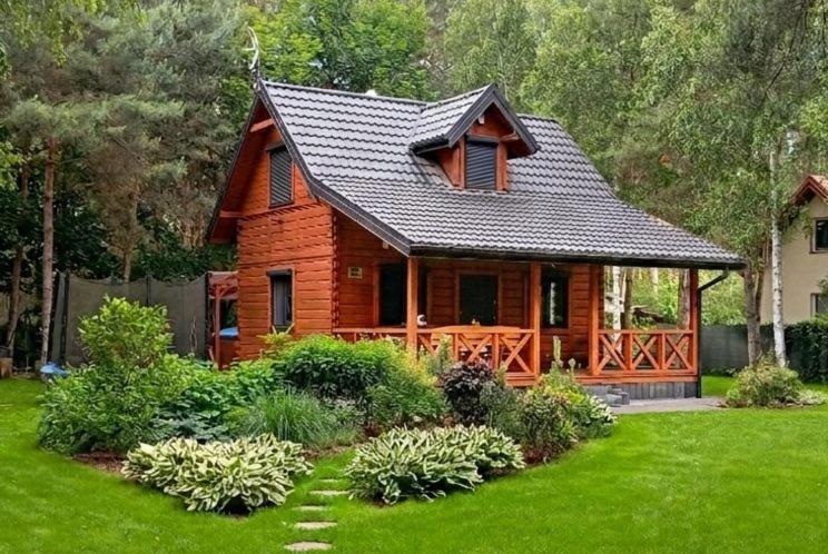 a wooden cabin in a yard with green grass at Otulina Gulczewo in Wyszków