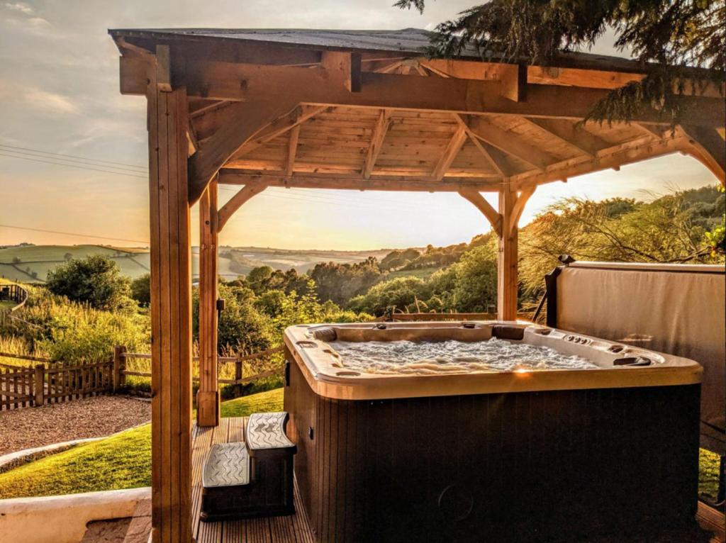 a hot tub under a wooden gazebo at Owl Barn in Saltash