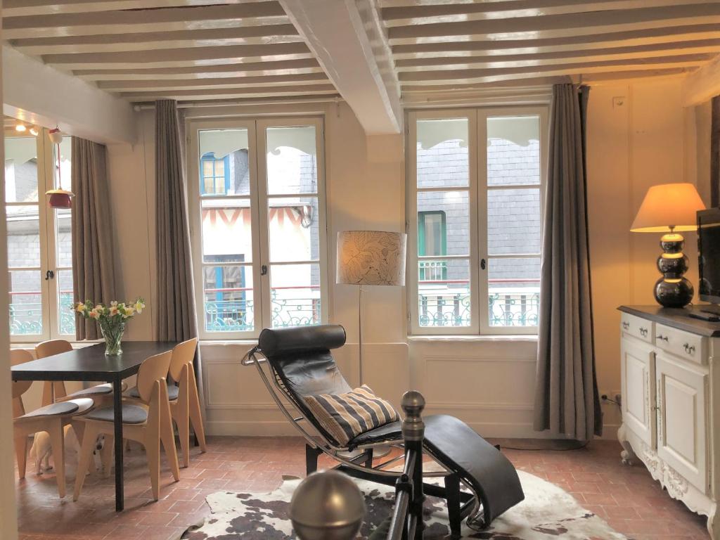 a living room with a chair and a table and windows at Appartement Le Notre Dame in Honfleur