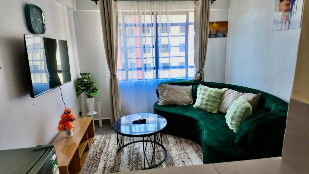 a living room with a green couch and a glass table at Gated executive 1 bed in gated near Top Malls, Kisumu in Kisumu