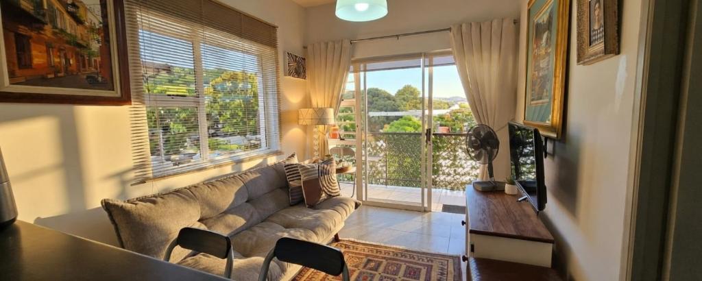 a living room with a couch and a large window at Little Nest One Bedroom Apartment! in Knysna