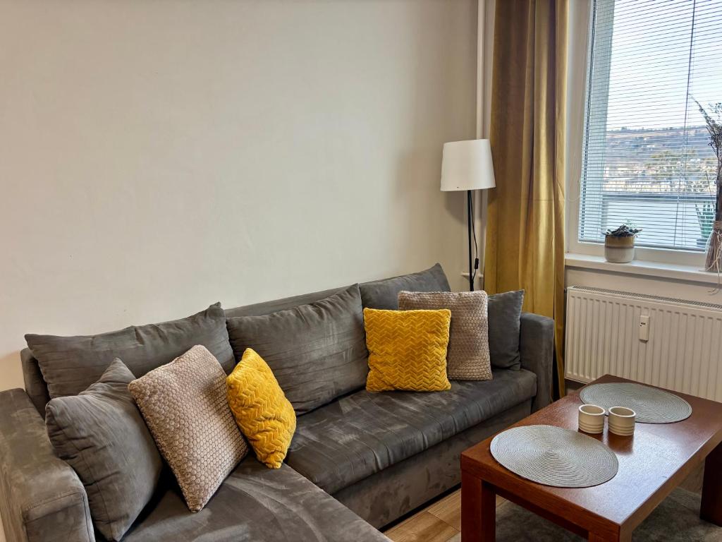 a living room with a gray couch with yellow pillows at City Ela Center in Košice