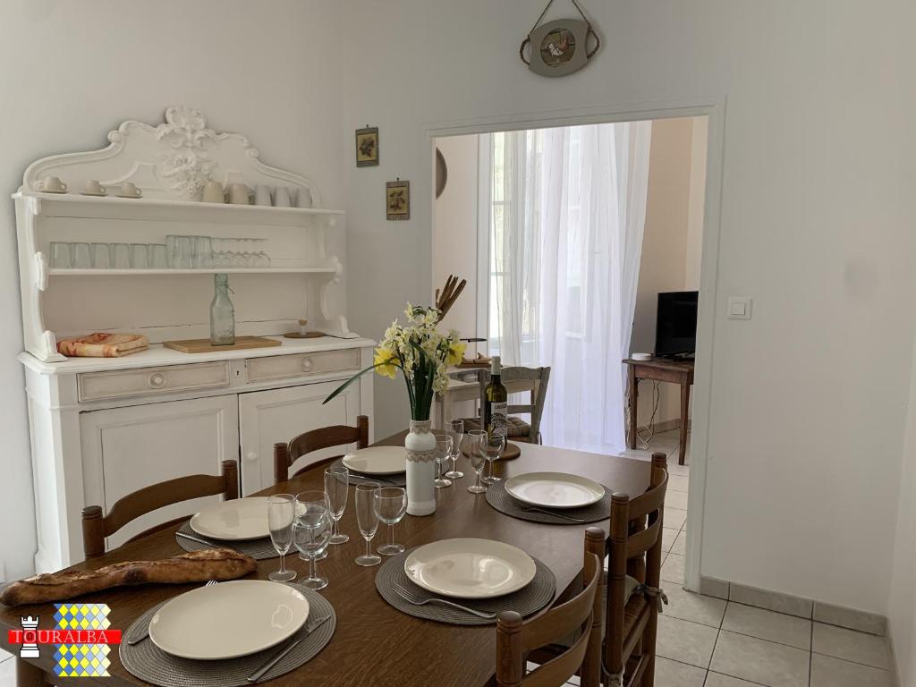 a dining room with a table and a kitchen at Echoppe Ancienne Boutique de cordonnier avec jardin privé in Aubeterre-sur-Dronne