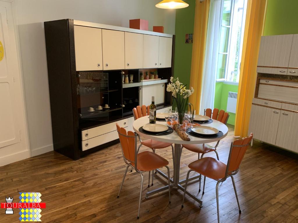 a dining room with a table and chairs and a kitchen at Barque Fleurie Maison Retro avec Jardin et Parking au coeur d'Aubeterre-sur-Dronne in Aubeterre-sur-Dronne