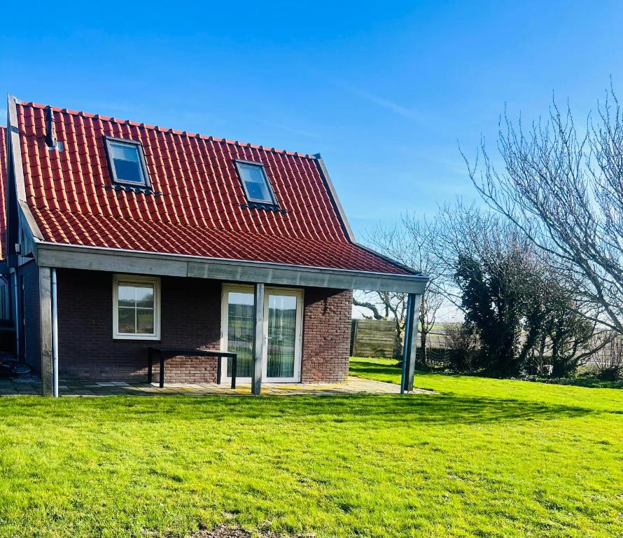 a house with a red roof on a green field at 't Olde Land in Den Burg