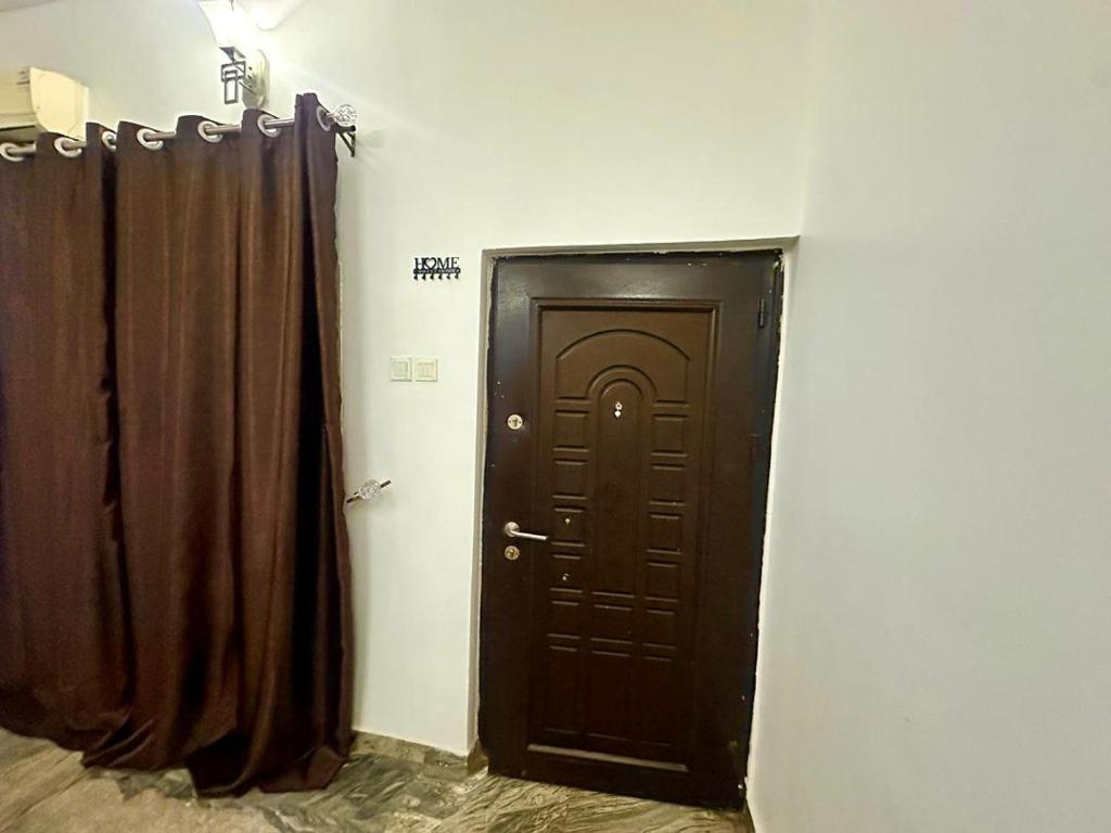 a hallway with a brown door and curtains at Resmay apartment in Abuja