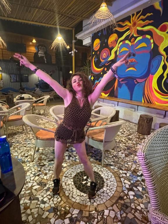 a woman standing in a room with her arms in the air at Simple Belle Stay ,Pool &Bar in Vagator