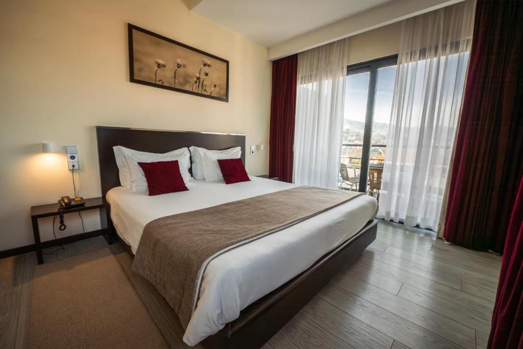 ein Hotelzimmer mit einem großen Bett mit roten Kissen in der Unterkunft Hotel Sao Pedro - Arouca in Arouca